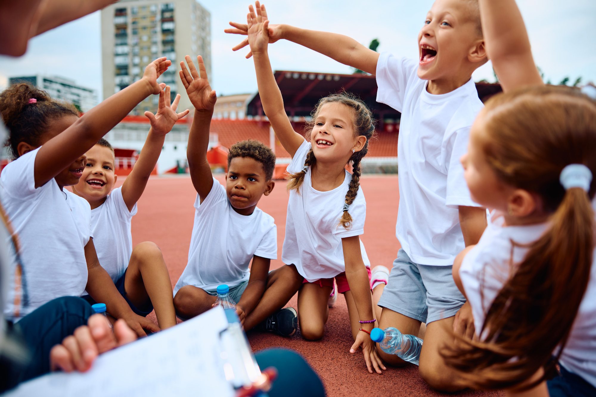 cheerful group of kids having fun during sports training at the stadium