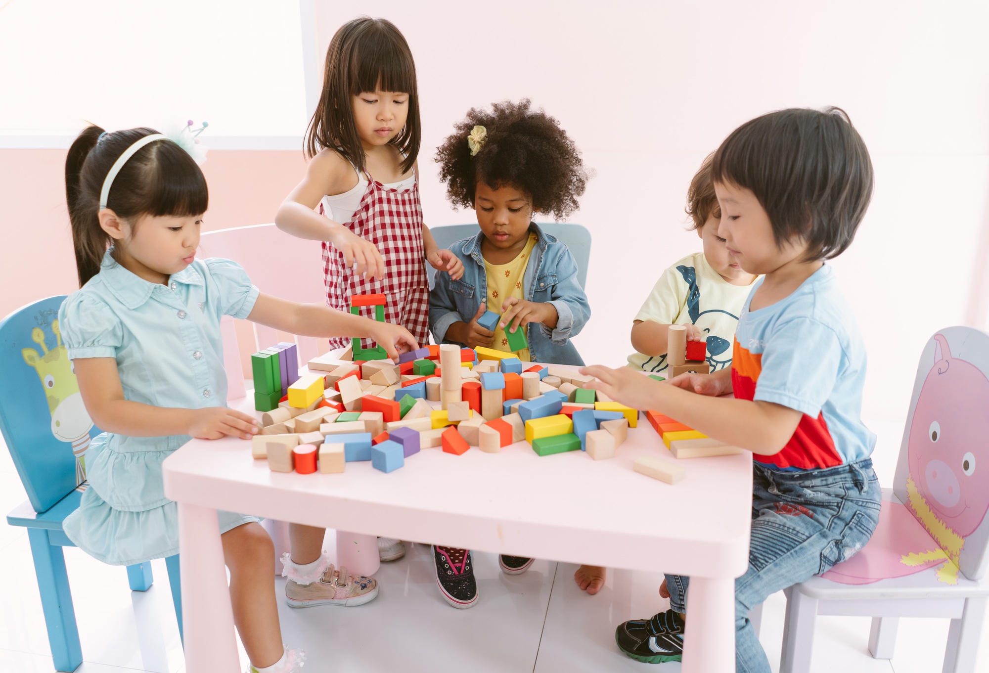 group of diversity kids playing with colorful blocks on table in class at the kindergarten
